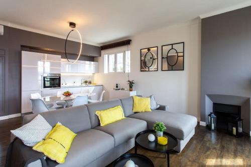 un salon avec un canapé gris et des coussins jaunes dans l'établissement #24 Marie-Claire Suite Sea view/balcony/AC/5min port, à Villefranche-sur-Mer