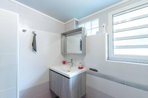 a white bathroom with a sink and a window at Charmant Studio Climatisé à Sainte Suzanne. in Commune Bègue