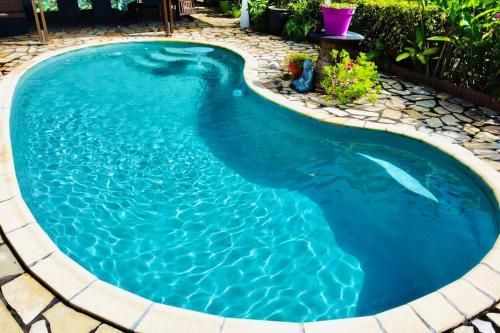 a swimming pool in a backyard with blue water at Charmant Studio Climatisé à Sainte Suzanne. in Sainte-Suzanne