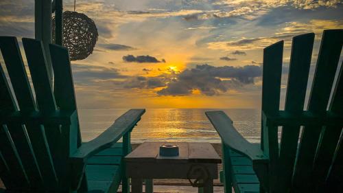 ランタ島にあるOzone Beach Houseのビーチの椅子2脚とテーブル、夕日付
