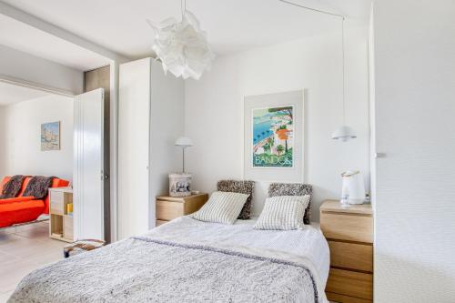 ein weißes Schlafzimmer mit einem Bett und einem roten Stuhl in der Unterkunft La Palmeraie - Appt climatisé - Piscine in Bandol