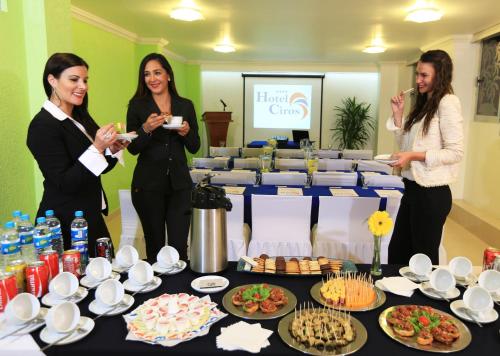 a group of three women standing next to a table with food at Hotel Ciros in Pachuca de Soto