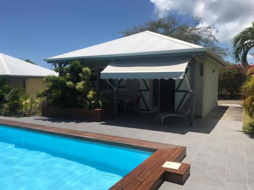 une maison avec une piscine et un parasol blanc dans l'établissement résidence Kaz'Tinou - Allo Sé Ann, à Saint-François