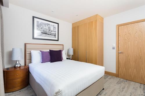a bedroom with a white bed and a wooden cabinet at Sanctum Belsize Road in London