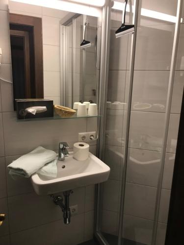 ein Bad mit einem Waschbecken und einer Dusche mit einem Spiegel in der Unterkunft Pension Pichler in Sillian