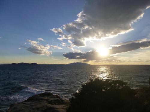 a sunset over the ocean with rocks in the foreground at Agriturismo Le Piane Del Milia in Suvereto