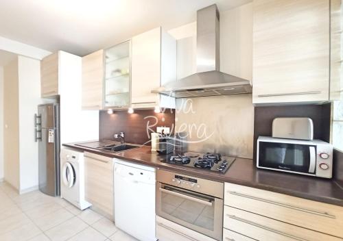 une cuisine avec des armoires blanches et un micro-ondes dans l'établissement Viva Riviera Rue Victor Cousin, à Cannes