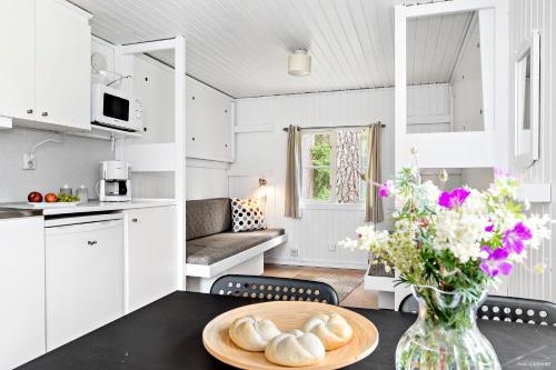 First Camp Kolmården-Norrköping في كولموردِن: مطبخ وغرفة معيشة مع طاولة مع إناء من الزهور