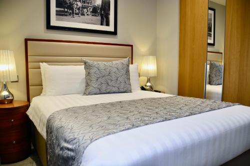a bedroom with a large bed and two lamps at Sanctum Belsize Road in London