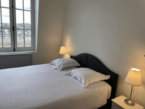 - une chambre dotée d'un grand lit avec des draps et des oreillers blancs dans l'établissement Le Royal XIX Vue mer, à Dinard