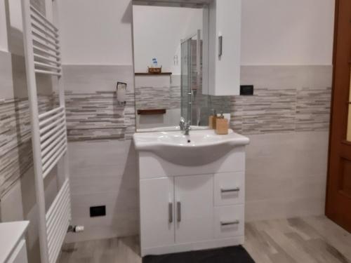 a white bathroom with a sink and a mirror at Grazioso bilocale Merlino, luminoso con vista Santuario, wifi in Giaveno