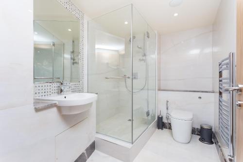 a white bathroom with a shower and a sink at Sanctum Belsize Road in London
