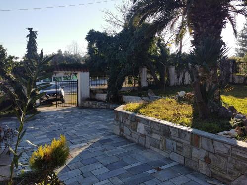 einen Garten mit einer steinernen Mauer und einem Zaun in der Unterkunft 160 s.m unique luxury house in Nea Kallikratia