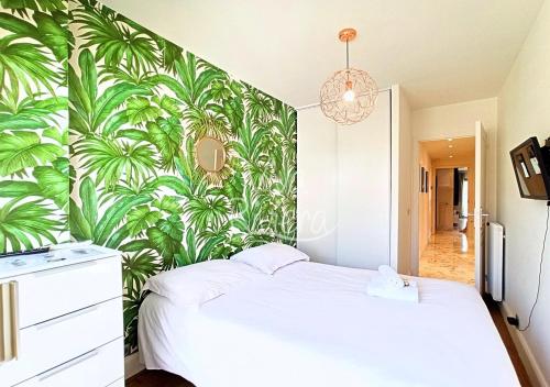 - une chambre avec un lit blanc et un papier peint tropical dans l'établissement Viva Riviera Luxury 2 Bedrooms Residence les Tuileries, à Cannes