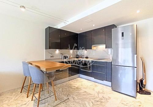une cuisine avec une table en bois et un réfrigérateur dans l'établissement Viva Riviera Luxury 2 Bedrooms Residence les Tuileries, à Cannes