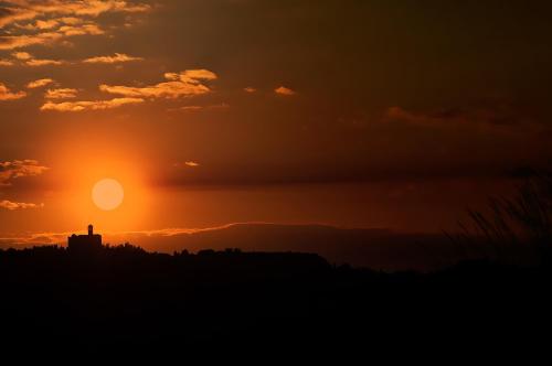 a sunset with a silhouette of a building on the horizon at Bed & Bike in Volterra