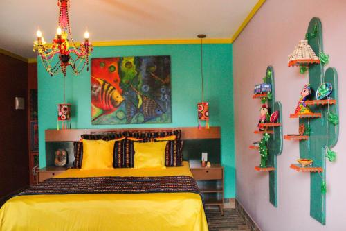 Un dormitorio con una cama amarilla y una pintura en la pared en Pousada No Meio do Mundo en Anchieta