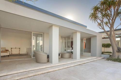 a white house with a patio with palm trees at Benguela Cove - Oceans Away in Hermanus