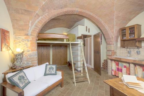 een woonkamer met een witte bank en een bakstenen muur bij CASA GIOVANNA in Castel San Gimignano