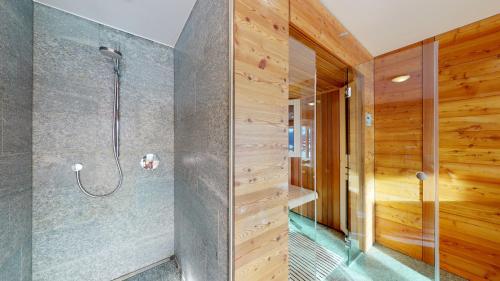 a shower in a bathroom with wooden walls at Etoiles des Neiges LUXE & JACUZZI chalet 12 pers by Alpvision Résidences in Hérémence