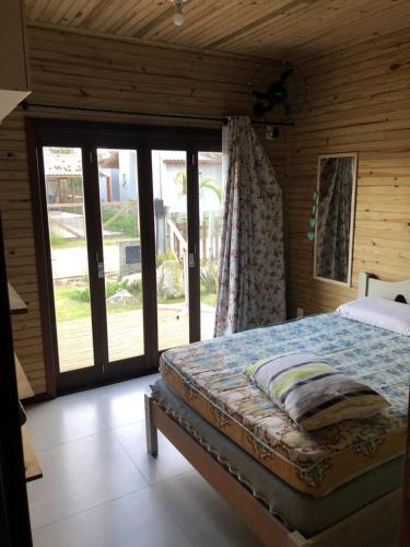 1 dormitorio con 1 cama y puerta corredera de cristal en Casa na praia do rosa, en Garopaba