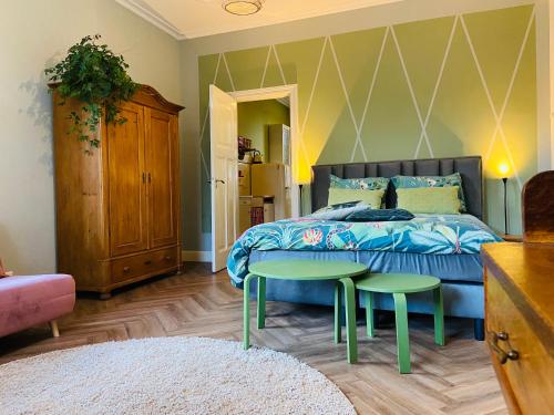 een slaapkamer met een bed en twee groene tafels en een bed bij De Oude Pastorie in Bunschoten