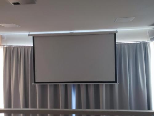 una pantalla de proyección en una habitación con cortinas en Ybira Loft, en Araxá