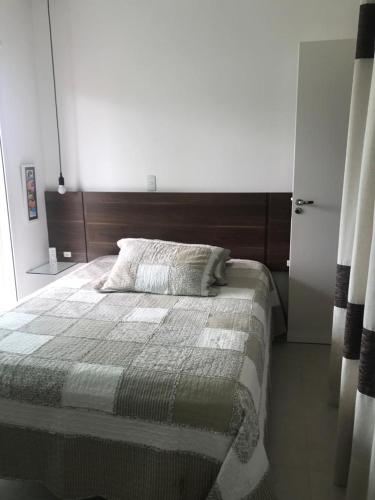 1 dormitorio con 1 cama grande y cabecero de madera en Apartamento encantador, 100 m do mar, en Porto Belo