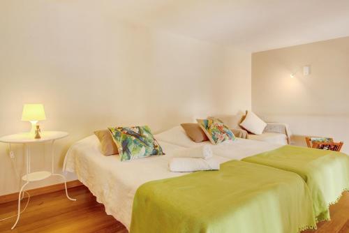 a bedroom with two beds and a table with a lamp at Calheta Lofts I in Calheta
