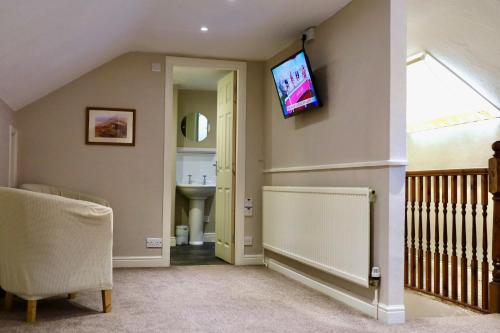 a living room with a tv on the wall at Sir William Hotel in Grindleford Bridge