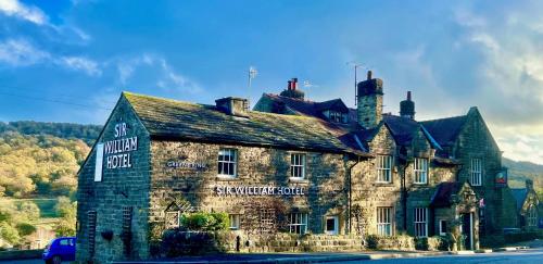 ein altes Steingebäude mit einem Schild drauf in der Unterkunft Sir William Hotel in Grindleford Bridge