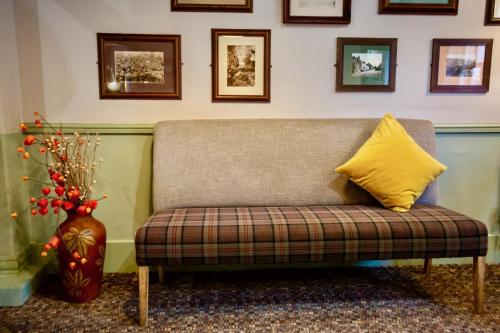 a couch with a yellow pillow and a vase at Sir William Hotel in Grindleford Bridge