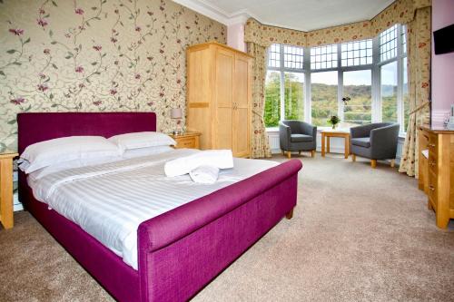 a bedroom with a large bed with a purple headboard at Sir William Hotel in Grindleford Bridge