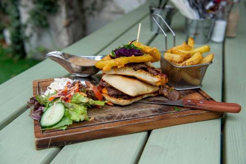 a sandwich and french fries on a cutting board with a salad at The Bailey bar & lounge in Athlone