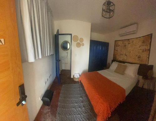 a bedroom with a bed with an orange blanket at Studio 27 Colonial, Centro Histórico in Santo Domingo