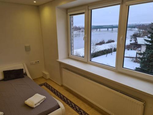 um quarto com uma cama e 2 janelas grandes em River view appartment in Kaunas em Kaunas