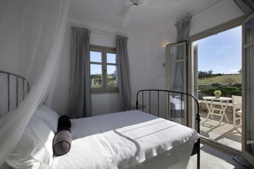 a bedroom with a bed and a balcony with a table at Kallisti Daphne · Gorgeous Villa - an oasis for 8 people in Naousa