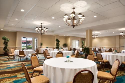 a banquet room with white tables and chairs and chandeliers at Wyndham Garden Wichita Downtown in Wichita