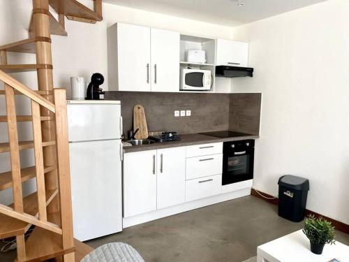 une cuisine avec des placards blancs et un escalier. dans l'établissement Calme à 10mn de l’aéroport d’Orly - Parking, à Orly