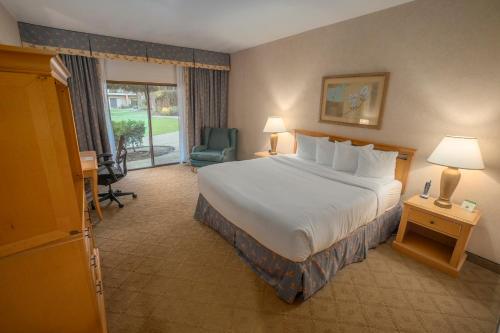 a hotel room with a bed and a chair at Piccadilly Inn Airport in Fresno