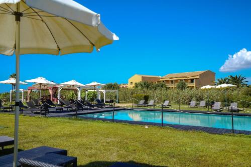 una piscina con sillas y una sombrilla junto a un complejo en Falconara Greenblu Resort, en Licata