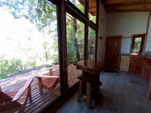 een kamer met een houten tafel en een groot raam bij Cabaña para dos en Conguillio in Melipeuco