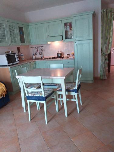 a kitchen with a white table and chairs in it at Casa sorriso in San Teodoro