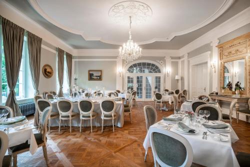 uma sala de jantar com mesas e cadeiras brancas e um lustre em Manowce Palace em Trzebieradz