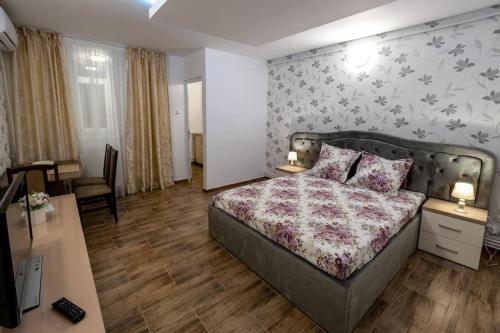 ein Hotelzimmer mit einem Bett, einem Schreibtisch und einem Schlafzimmer in der Unterkunft Luxury Radox Apartment Park 1 BZ in Buzău