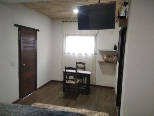 um quarto com uma mesa, uma cadeira e uma televisão em Chalé Suite do chá em Lavras Novas