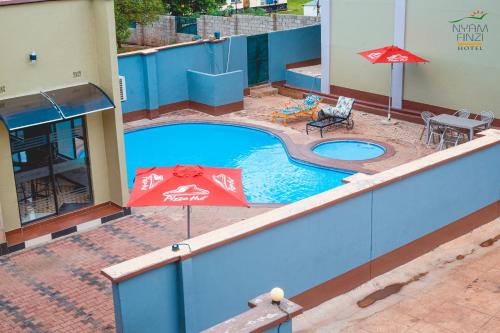 a swimming pool with an umbrella and a table and chairs at Nyamfinzi Hotel in Chipata