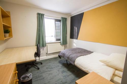 a bedroom with a bed and a desk and a window at Warwick Conferences - Central Campus Venues in Coventry