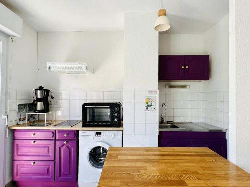 une cuisine avec des placards violets et un four micro-ondes dans l'établissement T2 calme avec balcon, parking et internet, Cambo-les-Bains - FR-1-495-46, à Cambo-les-Bains
