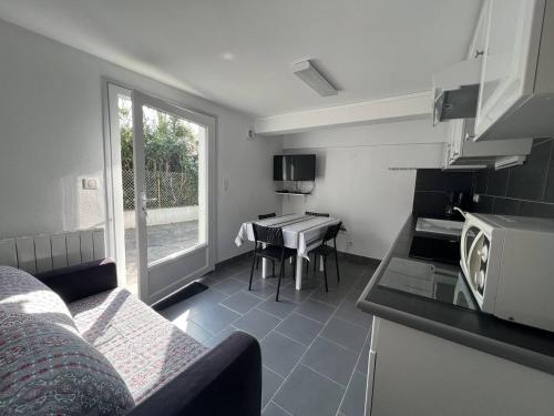 un salon avec une cuisine et une table avec un four micro-ondes dans l'établissement Coquet T1 Bis avec Terrasse en Rez-de-Jardin, Cambo-les-Bains - FR-1-495-91, à Cambo-les-Bains